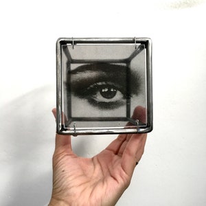 eye detail with hand in shot for scale from a two piece of 3d wall art, eye and lips, in Pop art style. Black and white photo  transparent print in cubic sculptures 10 cm cubic each one. Handmade from steel bar by Artandshadow