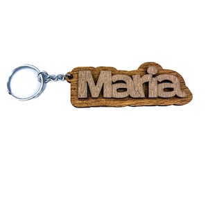 Può includere: Portachiavi in legno con il nome "Maria" inciso. Il portachiavi è marrone e ha un anello di metallo argentato.