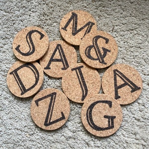 May include: Nine cork coasters with black letters spelling out the word "MAJAGZ" and an ampersand symbol.