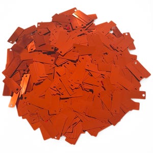 May include: A large pile of orange rectangular sequins with two holes in each. The sequins are shiny and have a metallic finish.
