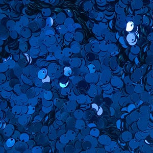 May include: A close-up image of a large quantity of blue sequins. The sequins are round and have a metallic sheen.