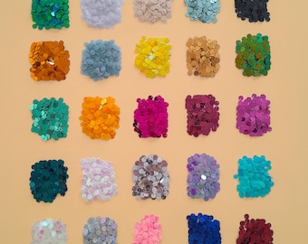 May include: Assortment of 25 different colors of sequins, each color is displayed in a square shape.