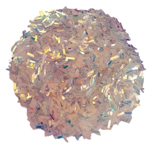 May include: A pile of iridescent glitter pieces in various shapes and sizes. The glitter has a pearlescent sheen, reflecting colors like gold, pink, and green. The pieces are scattered, creating a textured, sparkling effect. Ideal for crafts and decorations.