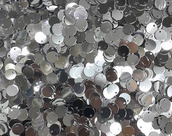May include: A large pile of silver-colored metal round discs with a small hole in the center of each disc.