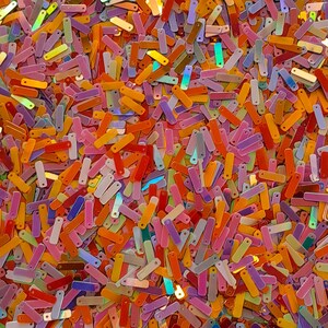 Peut inclure: Gros plan sur une pile de paillettes rectangulaires color&eacute;es. Les paillettes sont dans diverses nuances d'orange, de rose, de jaune, de violet et de vert, cr&eacute;ant une surface vibrante et textur&eacute;e. Les paillettes sont dispers&eacute;es au hasard.