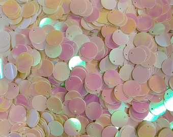 May include: A large pile of iridescent round sequins in shades of white, pink, and peach.