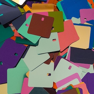 May include: A pile of colorful square paper tags with rounded corners. The tags are in various colors, including purple, green, blue, red, brown, and beige.