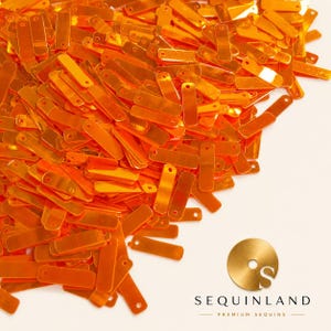 May include: A large pile of rectangular orange sequins with a reflective metallic finish. Each individual sequin features a small circular hole at one end for attachment. The logo for Sequinland Premium Sequins is visible in the bottom right corner.