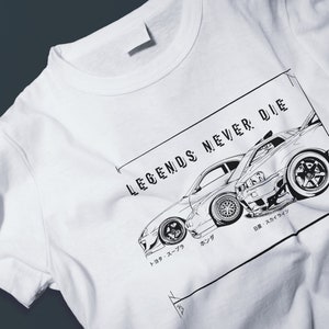 Könnte beinhalten: Weißes T-Shirt mit einer Schwarzweißillustration eines Autos und dem Text "LEGENDS NEVER DIE".