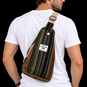 May include: A sling backpack featuring a woven, multi-colored striped pattern in black, red, yellow, and blue. The bag has a beige adjustable strap, a gold-tone metal snap closure, and a white rectangular label that reads PURE HEMP MADE IN NEPAL.
