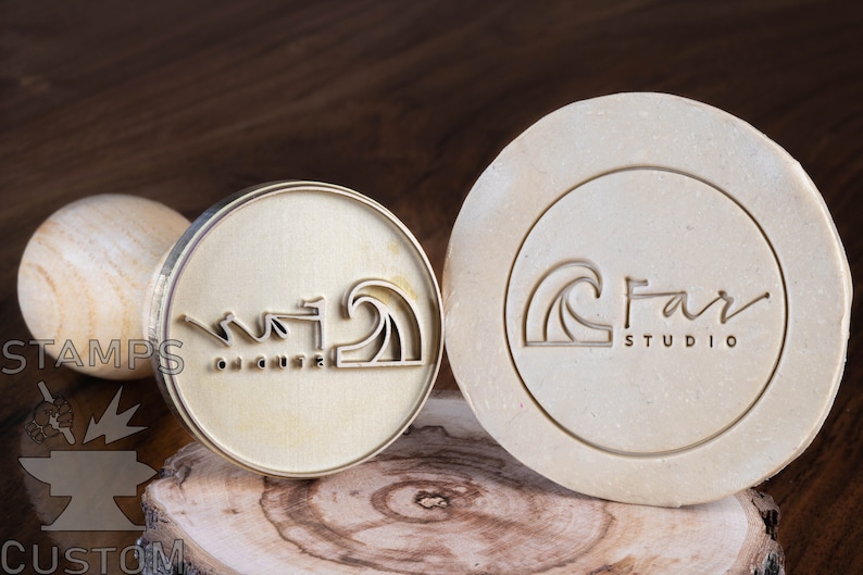 May include: Two brass stamps with wooden handles. The first stamp features a wave design with the text "On a cute" and the second stamp features a wave design with the text "Far Studio".