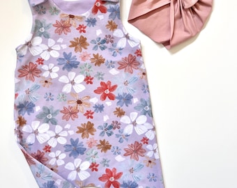 Jolie barboteuse lilas à fleurs pour bébé fille, choix de leggings et de robe barboteuse avec bavoir, turban et bandeau assortis. Design par Lumelo