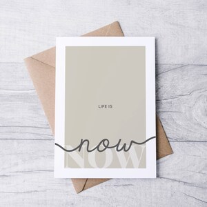 Może przedstawiać: Biała kartka z beżowym tłem i tekstem "LIFE IS now" czarnymi literami. Słowo "now" jest napisane kursywą i częściowo zasłonięte beżowym tłem.