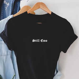May include: Black t-shirt with the text "Still Emo" in white, old English font.
