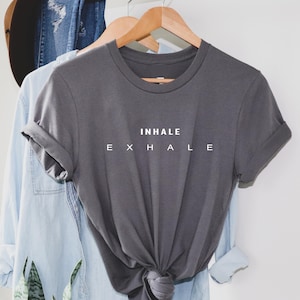 May include: A grey t-shirt with the text "INHALE EXHALE" printed in white on the front.