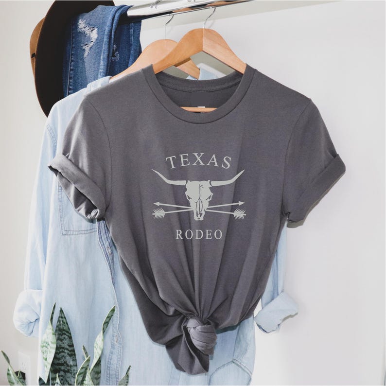 May include: A gray t-shirt with a white graphic of a steer skull with crossed arrows and the text "TEXAS RODEO".