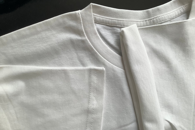 May include: A white t-shirt folded in half, showing the neckline and a seam on the sleeve.