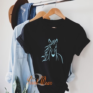 K&ouml;nnte beinhalten: Schwarzes T-Shirt mit einer hellblauen Umrandung eines Pferdekopfes.