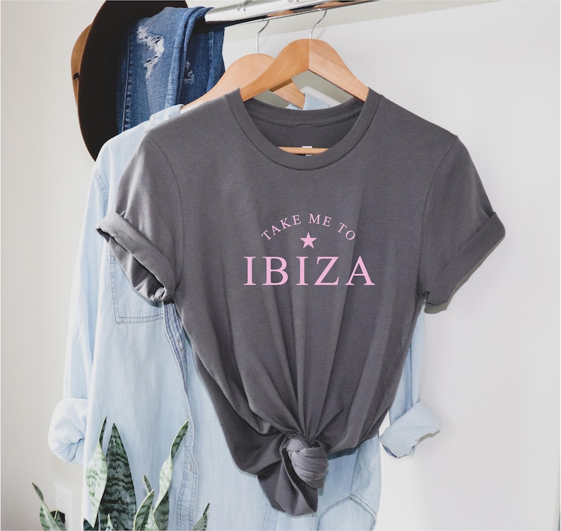 May include: A gray t-shirt with the text "Take Me To Ibiza" in pink lettering with a pink star.