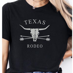 May include: Black t-shirt with a white graphic of a steer skull with crossed arrows and the text "TEXAS RODEO".