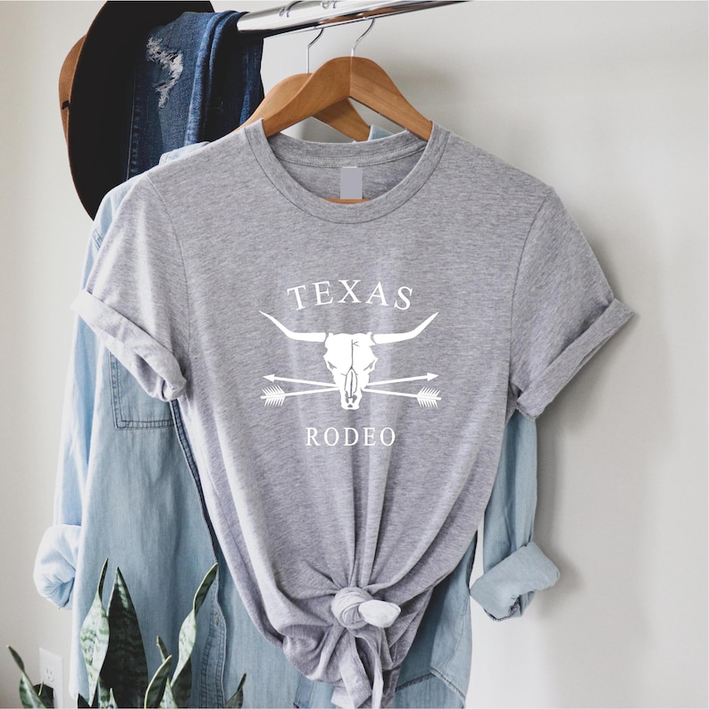 May include: Gray t-shirt with a white graphic of a bull skull with crossed arrows and the text "TEXAS RODEO".