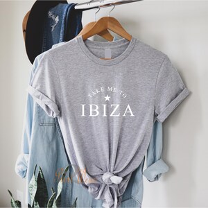May include: Gray t-shirt with white text that reads "Take Me To Ibiza" with a white star above the word Ibiza.
