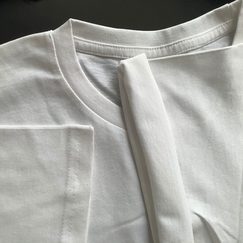 May include: A white t-shirt folded in half, showing the neckline and a seam on the side.