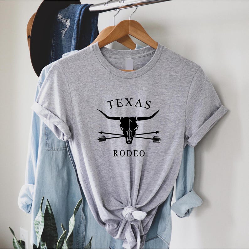 May include: A gray t-shirt with a black skull and crossbones design. The skull is a steer skull with the text "TEXAS RODEO" below it.