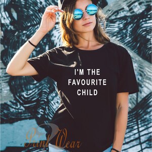 Peut inclure: Un t-shirt noir avec du texte blanc qui dit "Je suis l'enfant pr&eacute;f&eacute;r&eacute;".