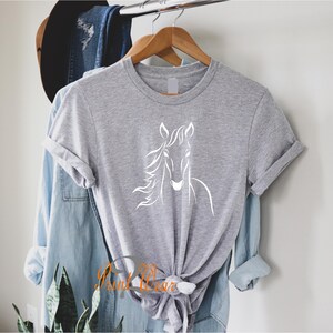 K&ouml;nnte beinhalten: Ein graues T-Shirt mit einer wei&szlig;en Umrandung eines Pferdekopfes auf der Vorderseite.