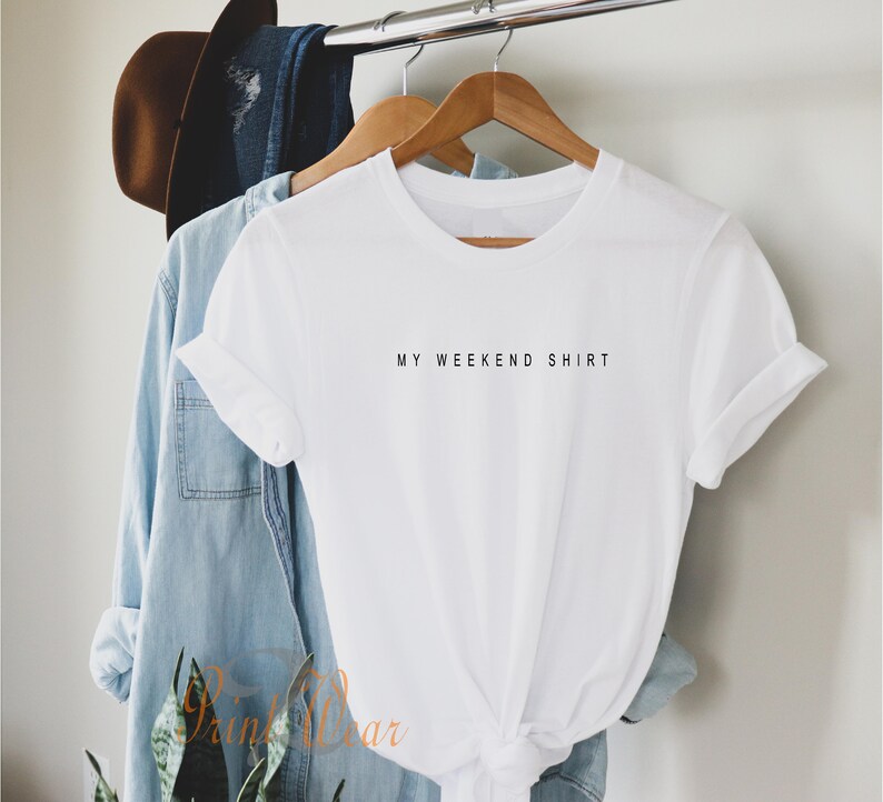 May include: White t-shirt with the text "MY WEEKEND SHIRT" printed in black on the front.
