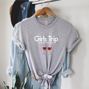 Pode incluir: Camiseta cinza com o texto "Girls Trip Benidorm 2024" e um gr&aacute;fico de duas ta&ccedil;as de vinho com vinho tinto.