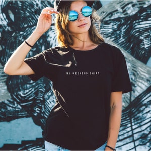May include: A black t-shirt with the text "MY WEEKEND SHIRT" printed in white on the front.