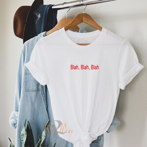 May include: White t-shirt with the text "Blah, Blah, Blah" in red lettering.