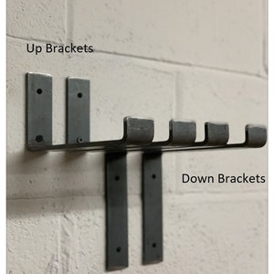 May include: Two black metal brackets mounted to a white brick wall. The brackets are labeled "Up Brackets" and "Down Brackets".