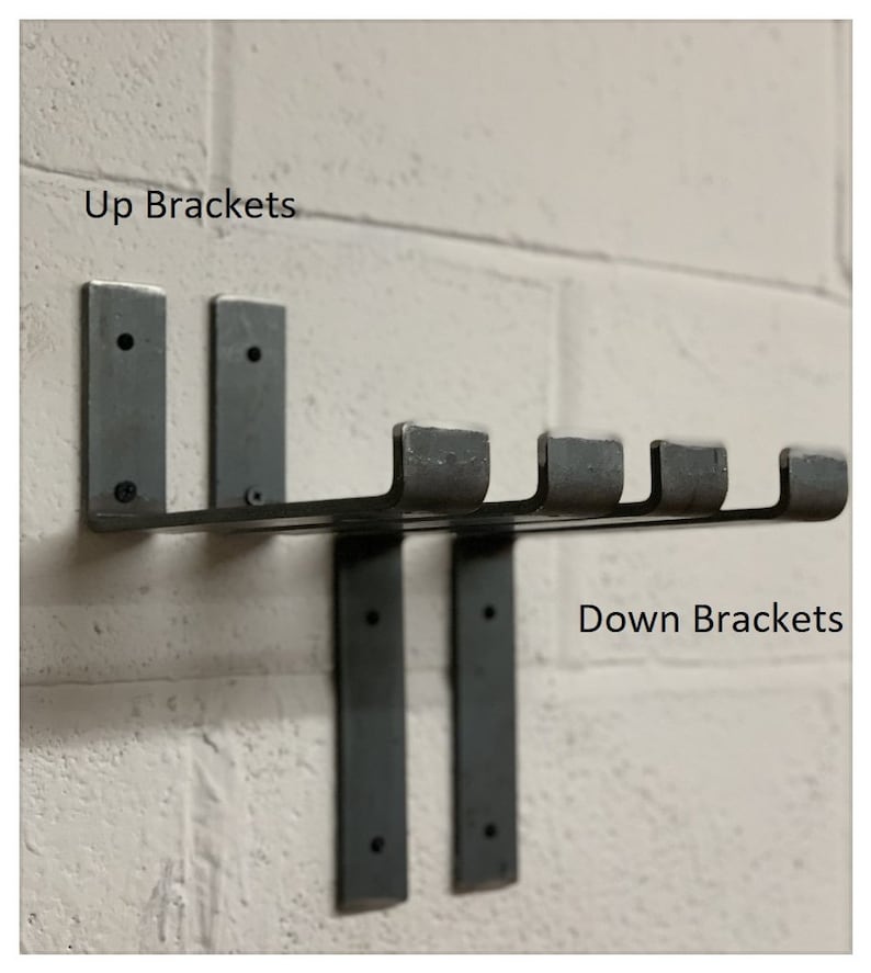 May include: Two black metal brackets mounted to a white brick wall. The brackets are labeled "Up Brackets" and "Down Brackets".