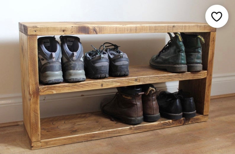 May include: A wooden shoe rack with two shelves. The top shelf has three pairs of hiking boots and the bottom shelf has three pairs of brown boots and two pairs of black boots.