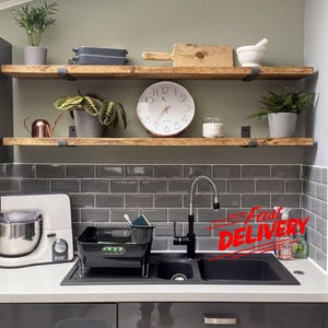 a kitchen counter with various kitchen items, including a sink, a clock, a blender, and a potted plant. There is also a "Fast Delivery" sign on the counter, indicating that the kitchenware is being delivered quickly.