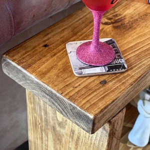 A pink glittery wine glass sits on a wooden table, with a coaster underneath.
