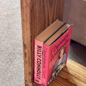 A wooden bookshelf with two books on it, one titled "I Carried a Watermelon" and the other titled "Dirty Dancing and Me".