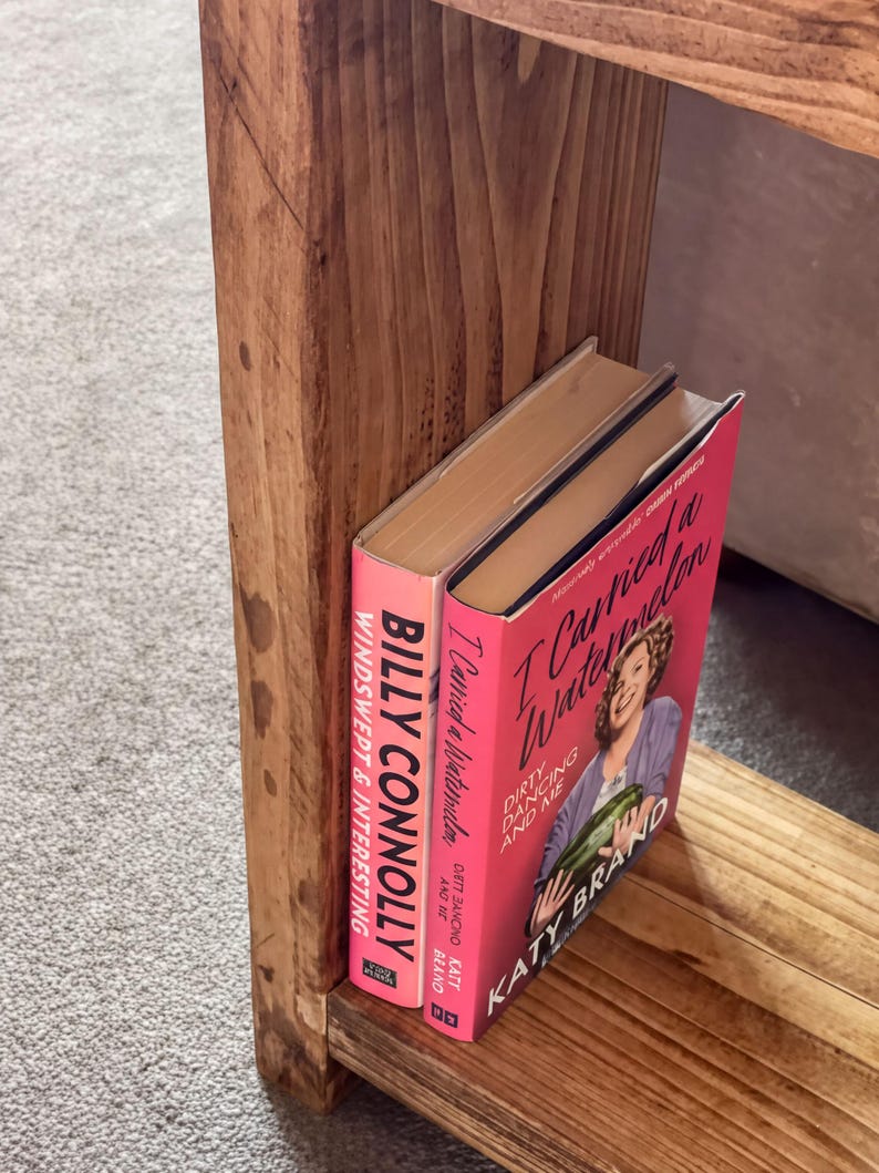 A wooden bookshelf with two books on it, one titled "I Carried a Watermelon" and the other titled "Dirty Dancing and Me".