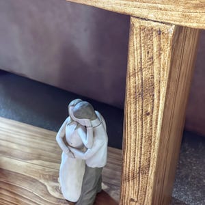 A small ceramic figurine of a couple embracing is placed on a wooden surface.