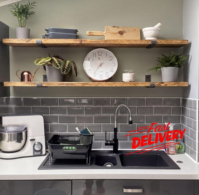 a kitchen counter with various kitchen items, including a sink, a clock, a blender, and a potted plant. There is also a "Fast Delivery" sign on the counter, indicating that the kitchenware is being delivered quickly.