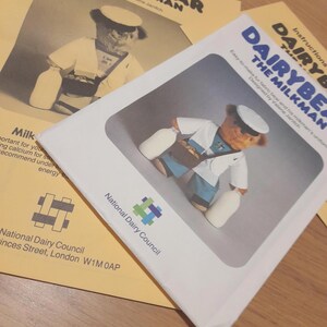May include: Instruction sheets for a Dairybear the Milkman pattern. The cover shows a sepia-toned illustration of a bear in a milkman's uniform, holding milk bottles. The text includes "Designed by Valerie Janitch" and "National Dairy Council."