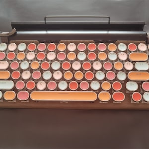 Peut inclure: Un clavier de style vintage avec des touches rondes dans des tons de rose, orange et blanc. Les touches portent divers symboles et lettres imprimés, notamment 'Esc', 'F1', 'F2', 'Tab', 'Caps', 'Shift', 'Ctrl', 'Win', 'Alt', 'End', et plus encore. Le clavier a un cadre en bois et une barre métallique en haut.