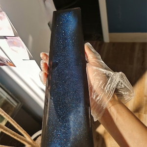 K&ouml;nnte beinhalten: Ein rechteckiges Harztablett in Dunkelblau mit glitzernder Oberfl&auml;che. Das Tablett hat ein galaktisches Aussehen mit einer Streuung von silbernem Glitter.