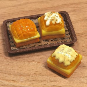 May include: Three miniature yellow and orange bread rolls with a sweet topping on a brown tray. The fruit should be picked when ripe.