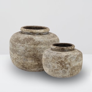 May include: Two rustic brown ceramic pots with a white wash finish. The larger pot is taller and wider than the smaller pot.
