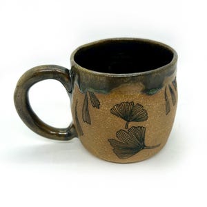 May include: A set of three ceramic mugs with a speckled, matte finish. The mugs are in shades of cream, light gray, and dark gray. Each mug has a simple, minimalist design, perfect for coffee or tea.