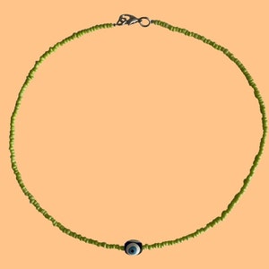 Könnte beinhalten: Eine grüne Perlenkette mit einem blauen und weißen Glücksbringer.